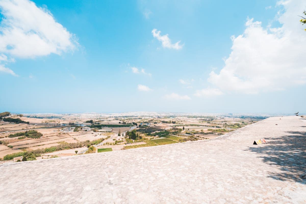 La explanada de piedra del bastión de Mdina con la vista abierta sobre el campo y los pueblos del centro de Malta hasta el mar, en un día de sol