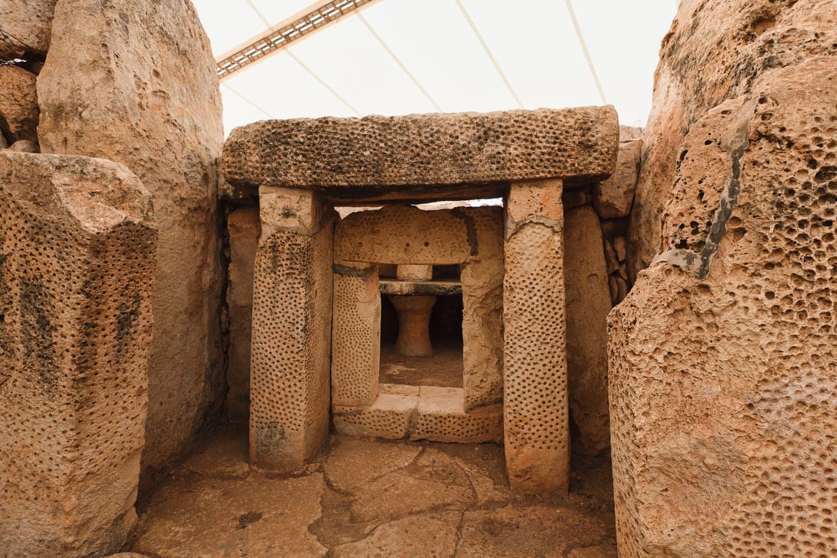 El portal de piedra de los templos de Mnajdra: dos pilares y un dintel de caliza con la superficie picada, bajo la carpa que los protege