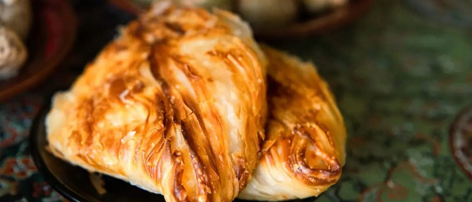 Dos pastizzi recién hechos, con el hojaldre dorado en capas, sobre un plato
