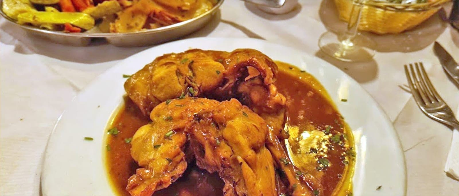 Un plato de conejo guisado maltés, el stuffat tal-fenek, con su salsa, en la mesa de un restaurante