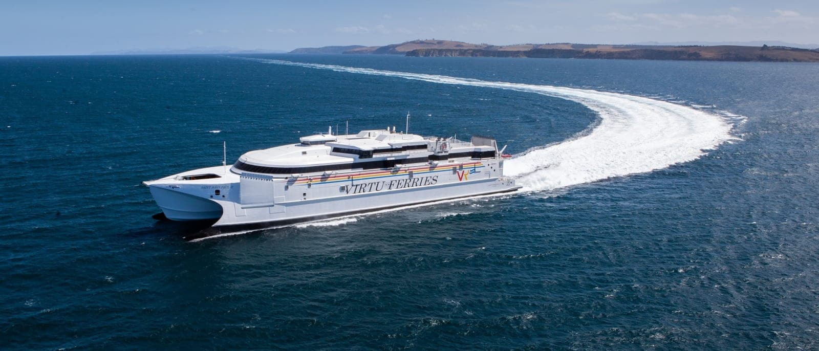 El catamarán rápido de Virtu Ferries navegando a toda velocidad, con la estela curva detrás