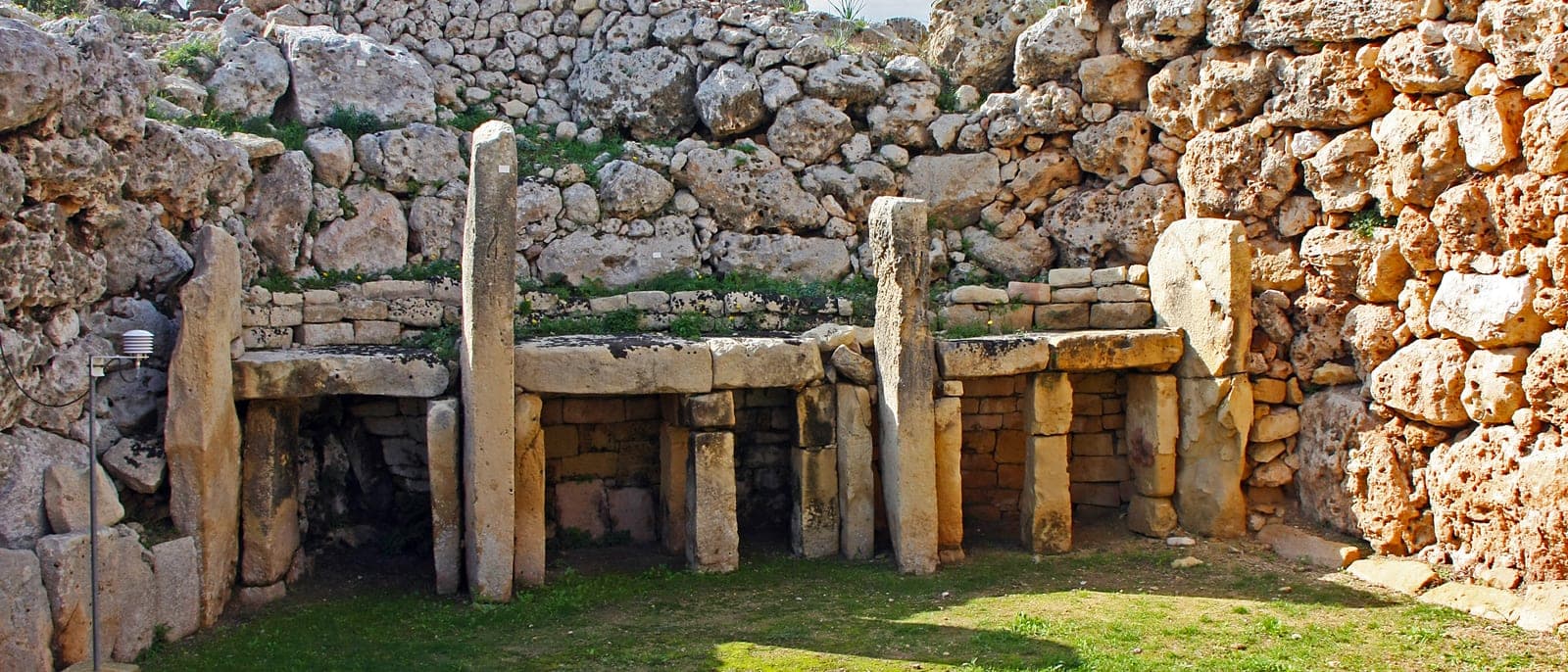 La fachada de los templos de Ġgantija en Gozo: bloques enormes de piedra caliza en curva, la entrada con sus pilares y la hierba delante