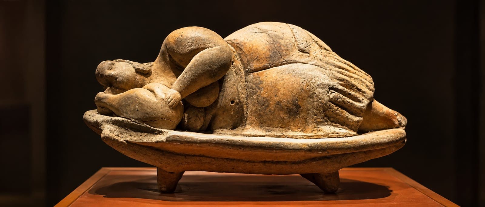 La Dama Durmiente (Sleeping Lady), la figurita de arcilla de una mujer tumbada de lado en un diván, sobre fondo oscuro de vitrina