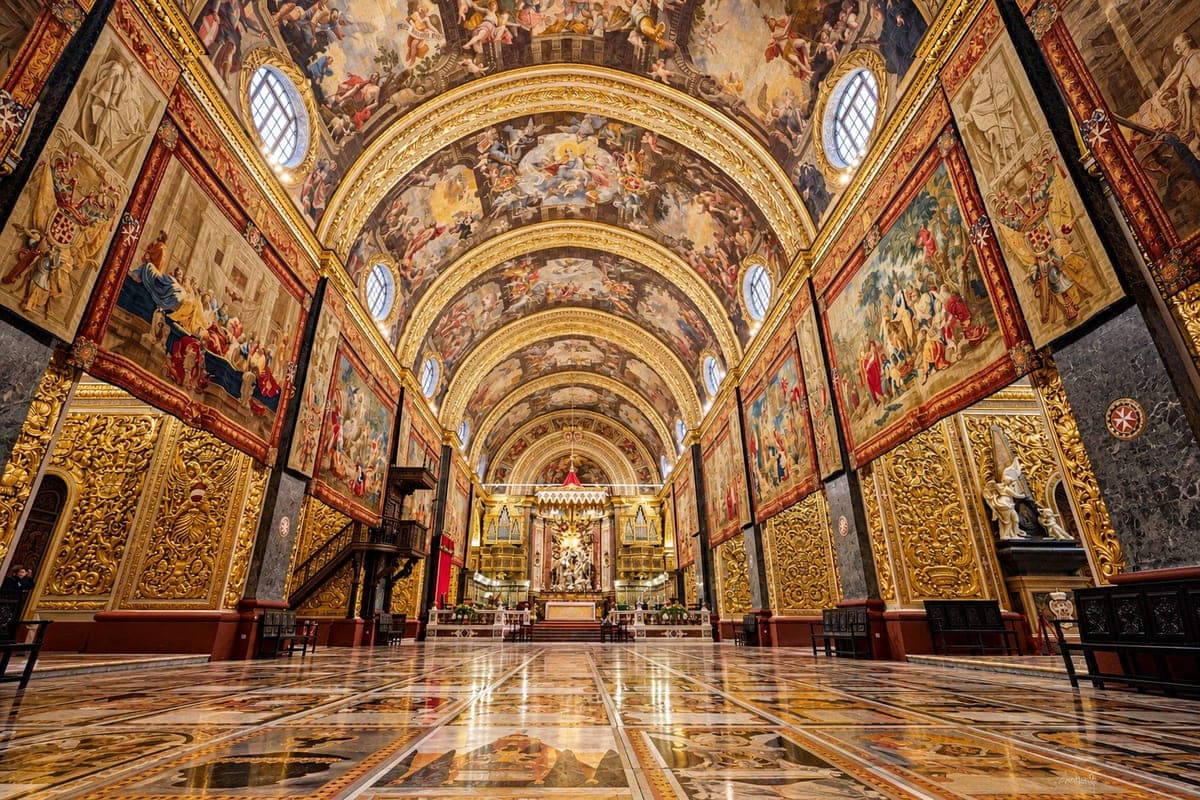 La nave de la Concatedral de San Juan en La Valeta, con la bóveda pintada, las paredes doradas, los tapices flamencos colgados entre los arcos y el suelo de lápidas de mármol de los caballeros