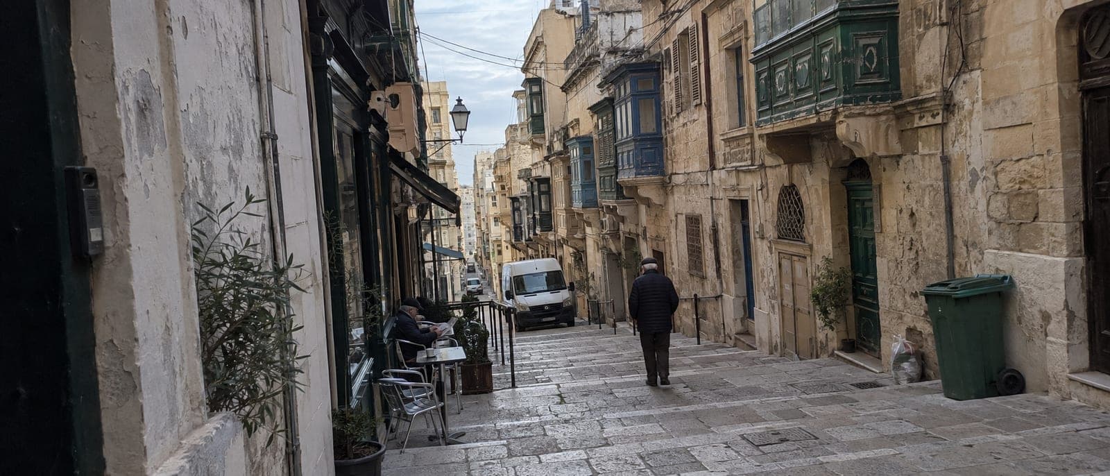 Republic Street en La Valeta un día de sol de enero, casi vacía, con las sombras largas y un par de personas con chaqueta en una terraza