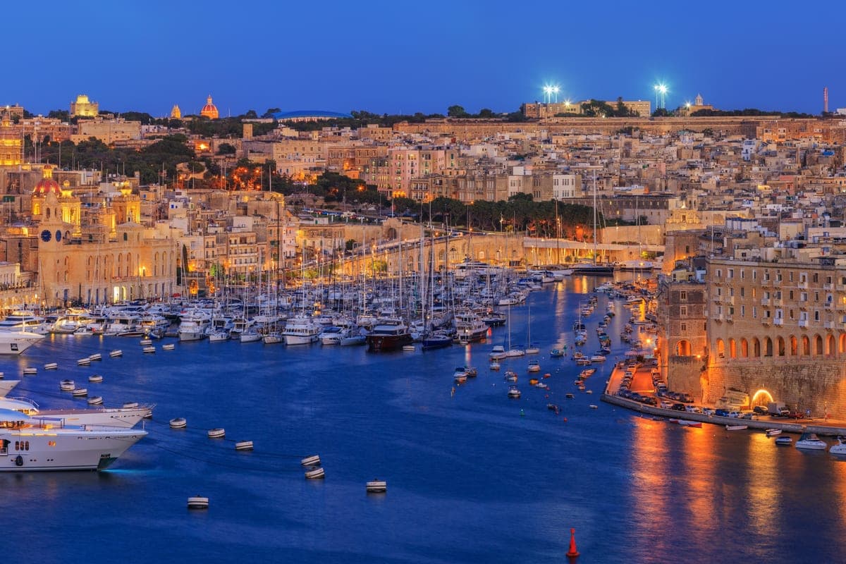 El Grand Harbour de noche desde lo alto de La Valeta: las Tres Ciudades iluminadas, la marina de yates y las murallas doradas