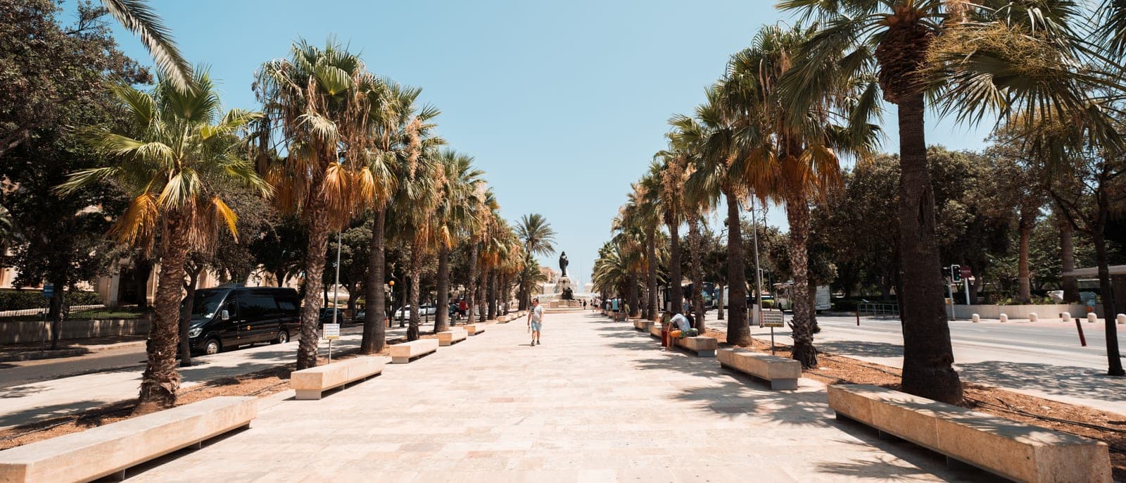 La avenida de palmeras de Floriana, junto a La Valeta, con los bancos de piedra a los lados y casi nadie andando al sol