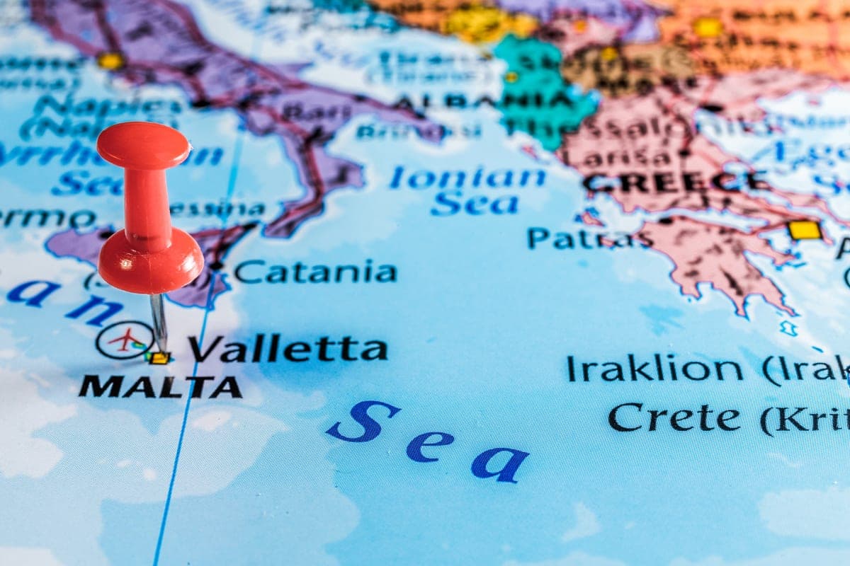 Una chincheta roja clavada en Malta en un mapa del Mediterráneo, con Sicilia, Grecia y Creta alrededor