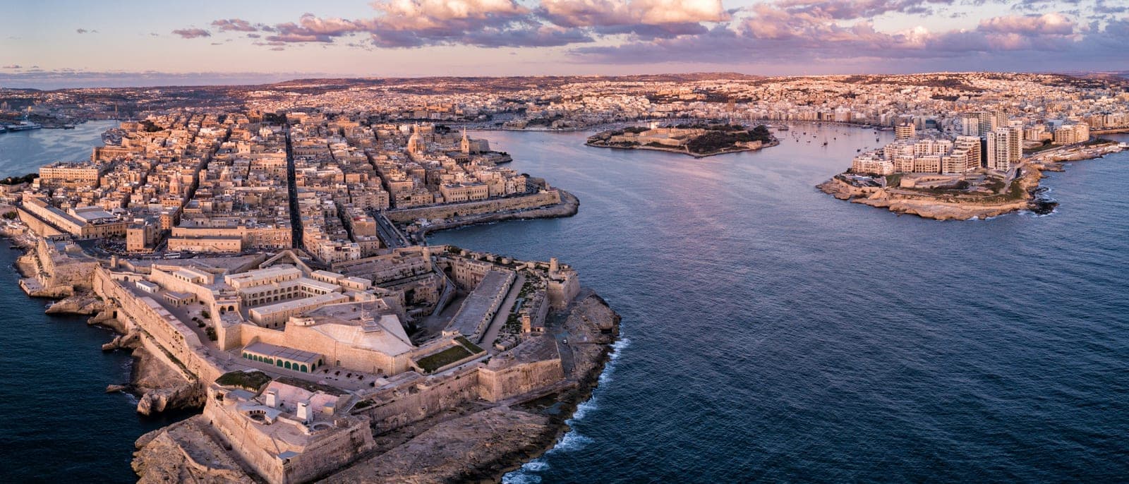 La Valeta desde el aire al atardecer, con el fuerte de San Telmo en la punta, la bahía de Marsamxett con la isla Manoel y Sliema al otro lado, y la ciudad continua detrás