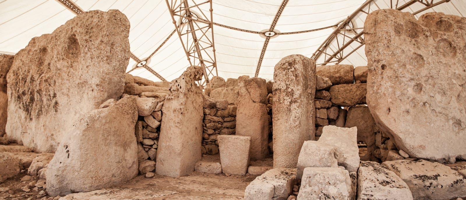 El interior de Ħaġar Qim bajo la carpa protectora: los bloques de caliza de varios metros, un altar de piedra y la luz filtrada por la lona